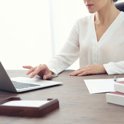 woman works at office; she is wearing a silky blouse for work