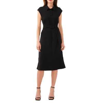 A woman wearing a black midi cap sleeve dress and black heels