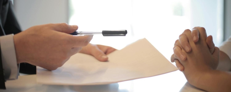 man interviews woman, holding resume and gesturing with his pen; he might just be asking her to the