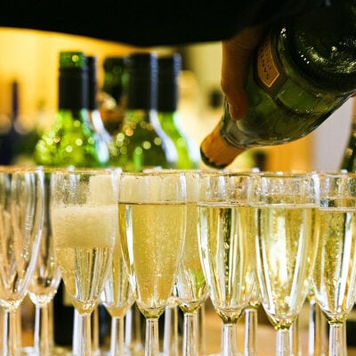 champagne glasses sit on a bar; a server is pouring more champagne