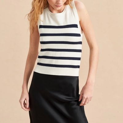 A woman wearing a sleeveless black and white stripe top and silk skirt