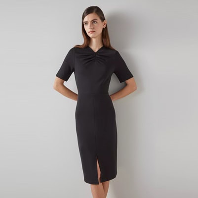 A woman in a black sheath dress with front slit