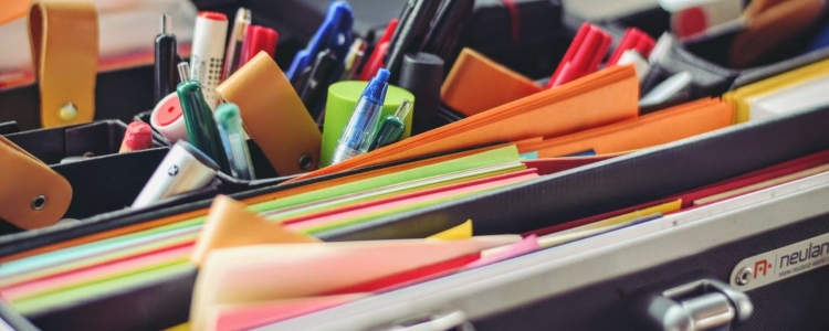 multi-colored office supplies peeking out of an desk drawer