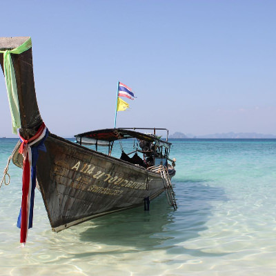boat anchored at shore in shallow waters; in the distance you can see the horizon, a sky near dusk, and darker water