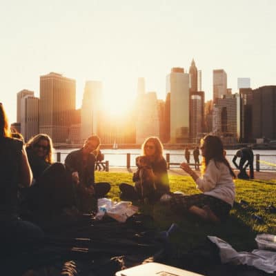 group of young professionals eating outdoors at sunset; they may be attending a company picnic