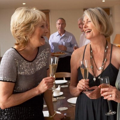 older, polished people laugh at a holiday dinner party