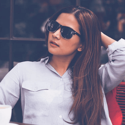 young professional woman looks hot while sitting outside; she is wearing summer work clothes of a blue button-front shirt and black pants