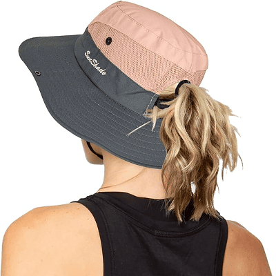 woman wears gray and pink sun hat that has a space for her ponytail to come out the back