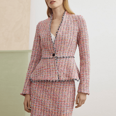 woman wears light pinky orange tweed skirt suit with a peplum detail at the waist